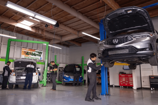Electron Automotive shop with technician inspecting gray Acura on lift