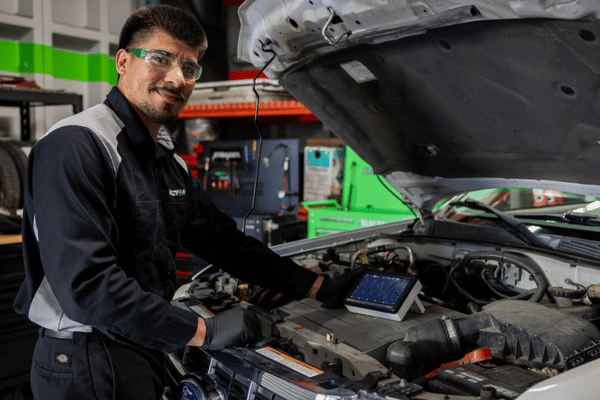 Electron Automotive technician using diagnostic tablet under car hood