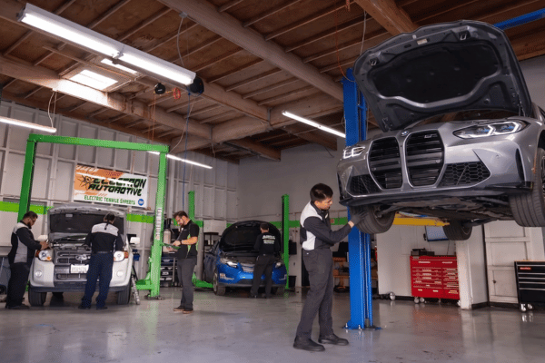 Electron Automotive shop with technician inspecting gray BMW on lift