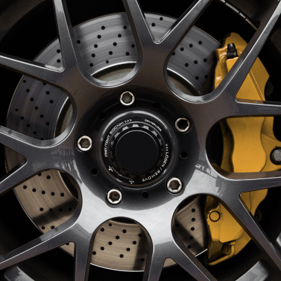 Close-up of a car wheel with a gray rim, yellow brake caliper, and perforated brake disc.