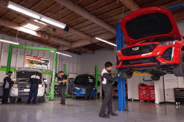 Electron Automotive shop with technician inspecting red Cadillac on lift