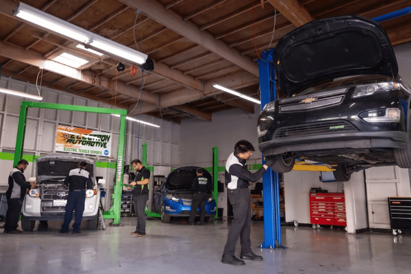 Electron Automotive shop with technician inspecting black Chevrolet on lift