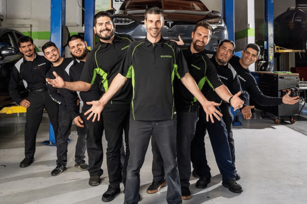 Electron Auto team standing in a garage in front of a car, smiling and posing together