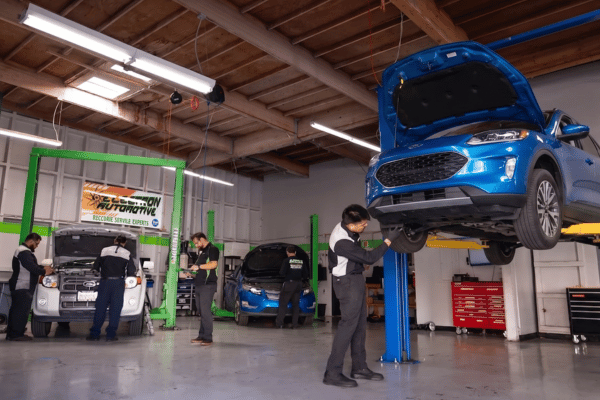Electron Automotive shop with technician inspecting blue Ford on lift