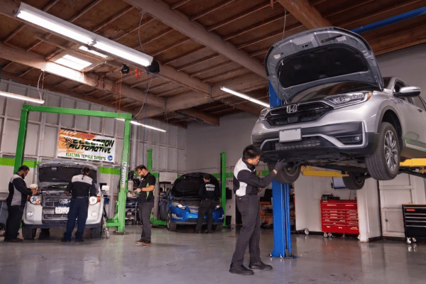 Electron Automotive shop with technician inspecting silver Honda on lift