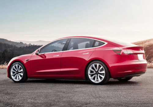 Red sedan parked on an open road with scenic hills in the background.