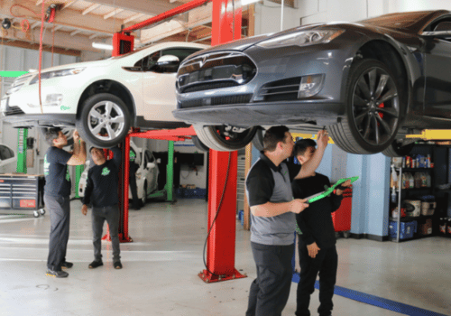 Auto repair shop with technicians inspecting vehicles on lifts, performing auto diagnostics.