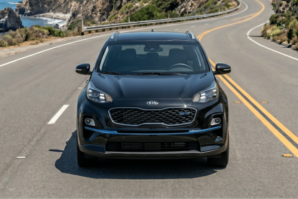 Black Kia SUV driving on coastal road