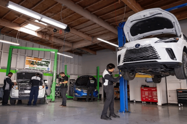 Electron Automotive shop with technician inspecting white Lexus on lift