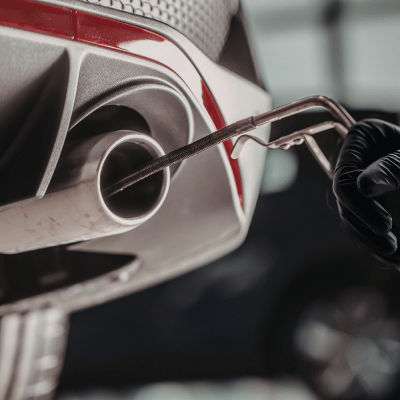 Close-up of car exhaust being tested for emissions with a probe.