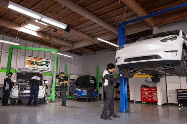 Electron Automotive shop with technician inspecting white Tesla on lift