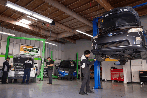 Electron Automotive shop with technician inspecting gray Toyota on lift