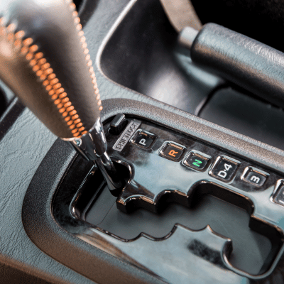 Close-up of a car's automatic gear shift lever, black leather and chrome, in 