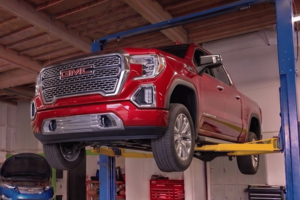 Red GMC pickup truck raised on lift