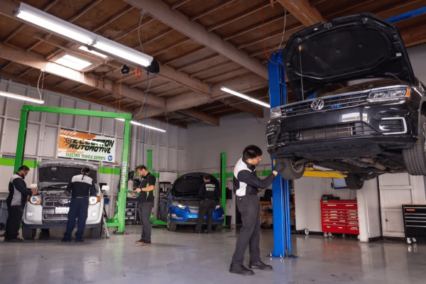 Electron Automotive shop with technician inspecting black Volkswagen on lift