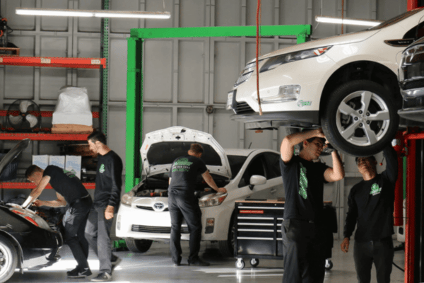 Electron Automotive repair shop with technicians working on multiple vehicles on lifts