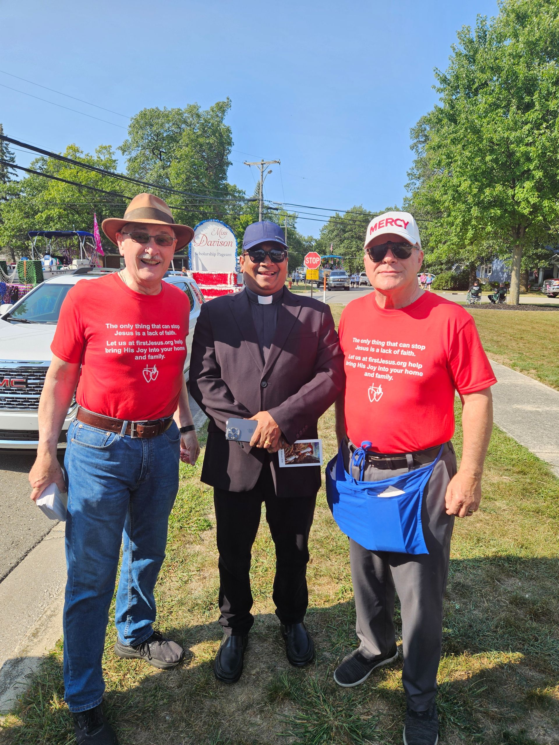 Three men are standing next to each other on the side of the road. priest