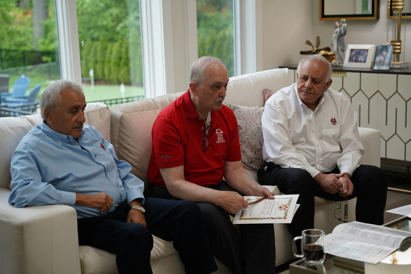Three men are sitting on a couch in a living room for home enthronement