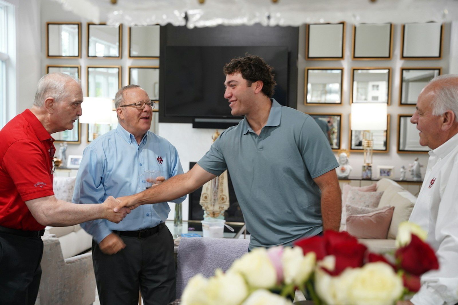 A group of men are shaking hands in a living room.