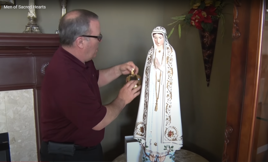 A man is standing next to a statue of the virgin mary