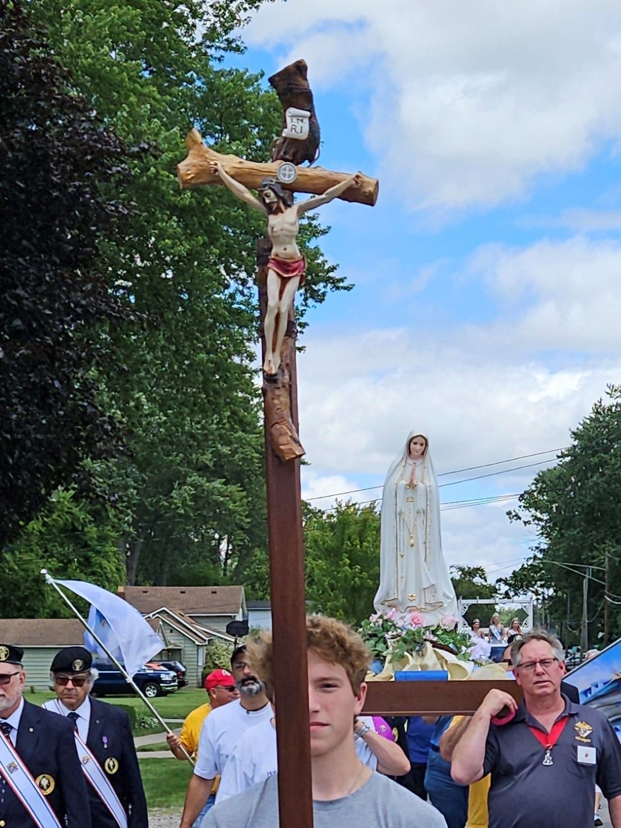 A man carrying a cross with Jesus on it and our Lady of Fatima statue