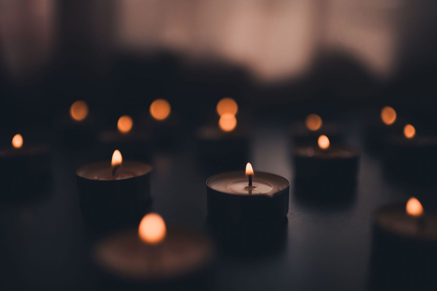 A group of lit candles are sitting on a table in the dark.