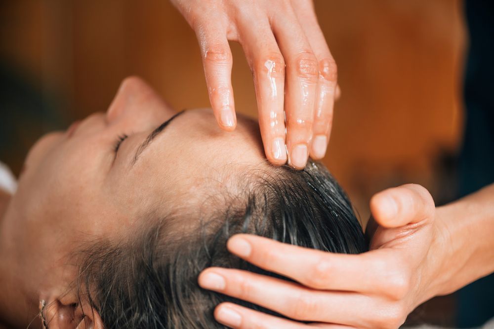Person receiving a scalp massage with hands gently pressing the forehead and head