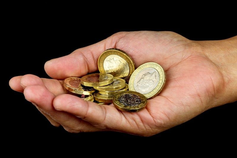 Hand holding a small pile of gold coins against a black background.