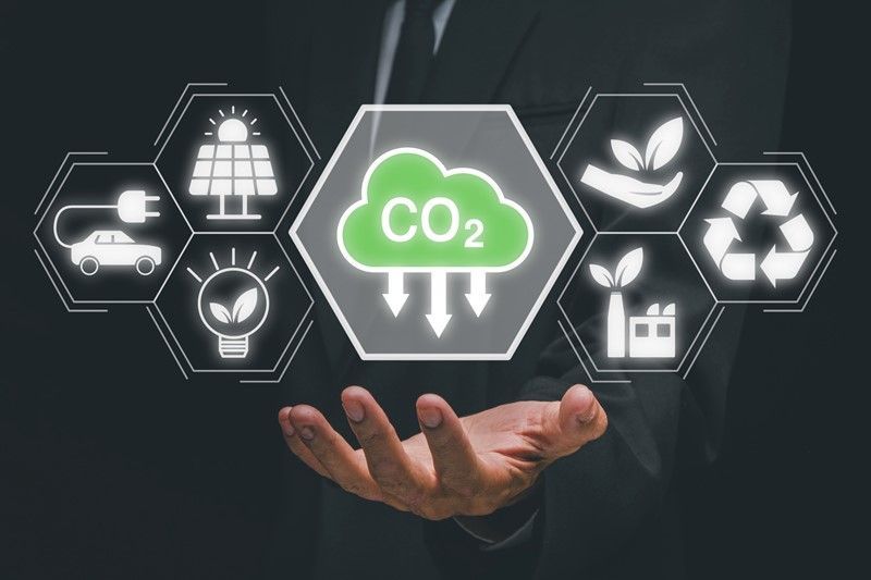 Man holding a graphic of a green cloud with CO2 and icons representing renewable energy sources.