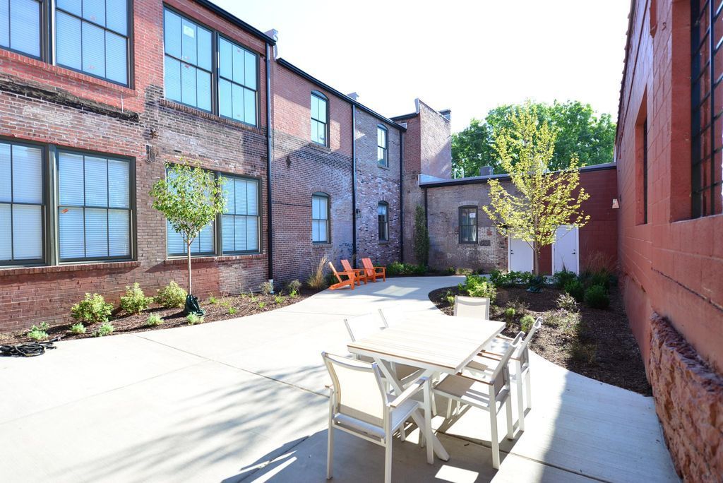 A patio with a table and chairs in front of a brick building