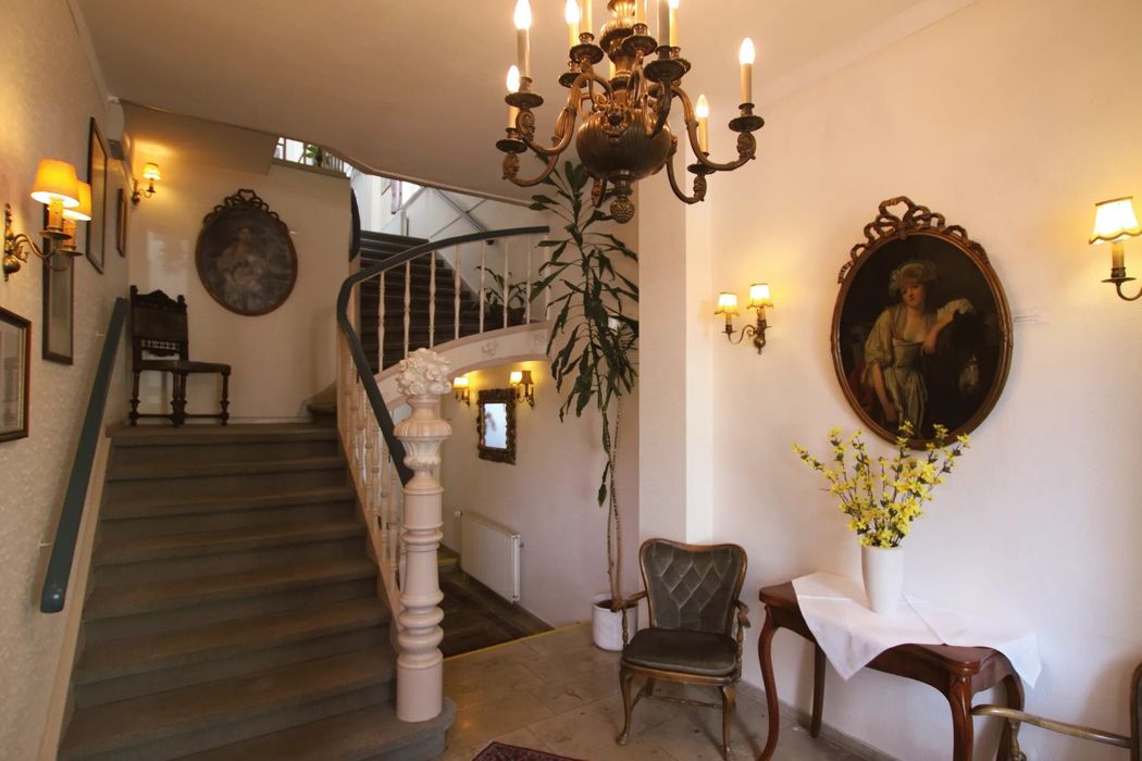 Ein Flur mit Treppe und einem Kronleuchter, der von der Decke hängt