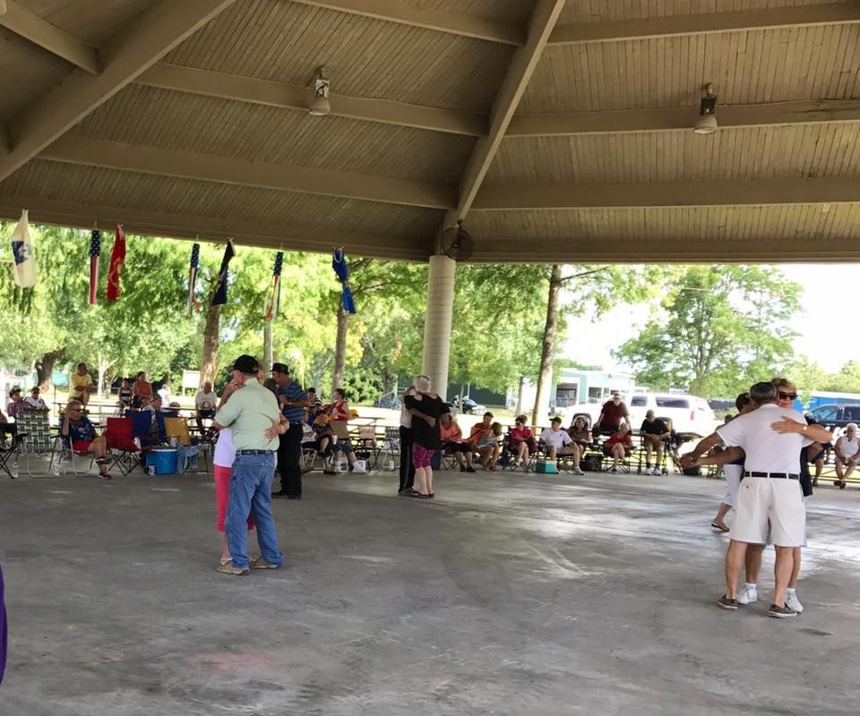 A group of people are dancing under a covered area