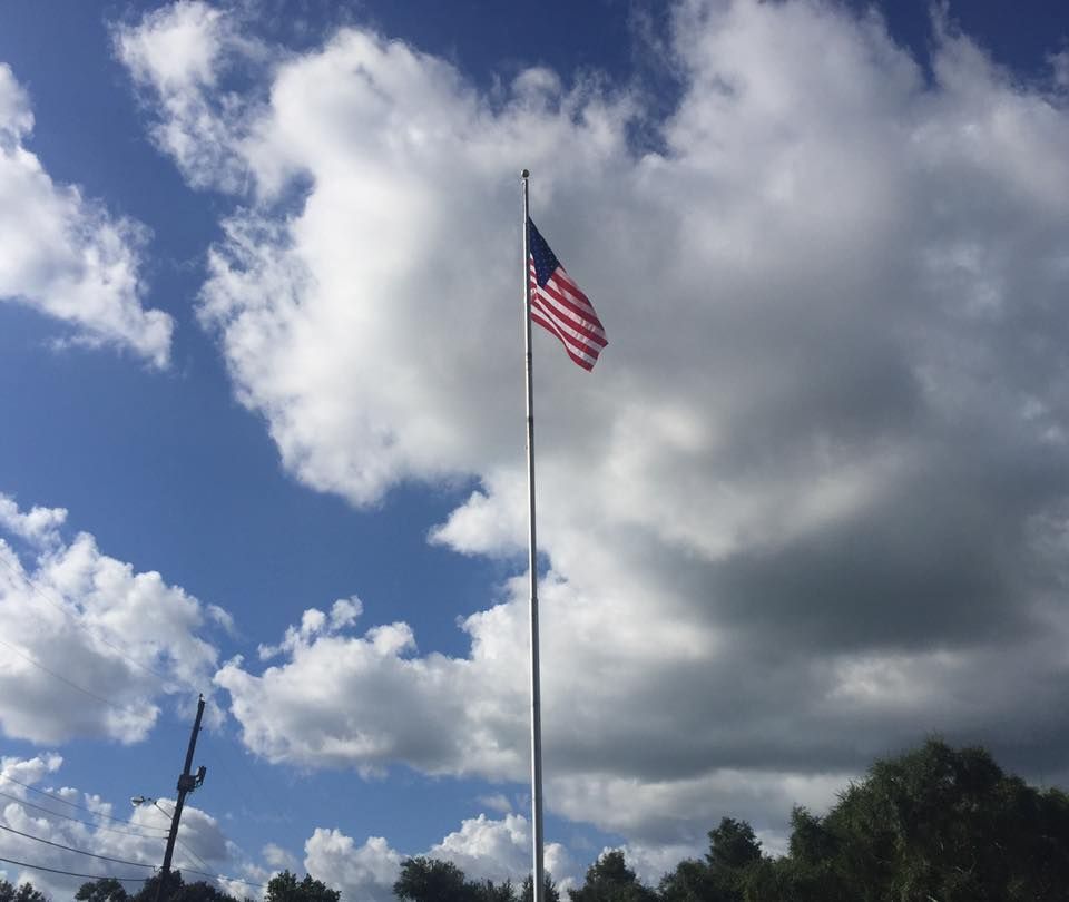 An american flag is flying in the wind against a cloudy sky