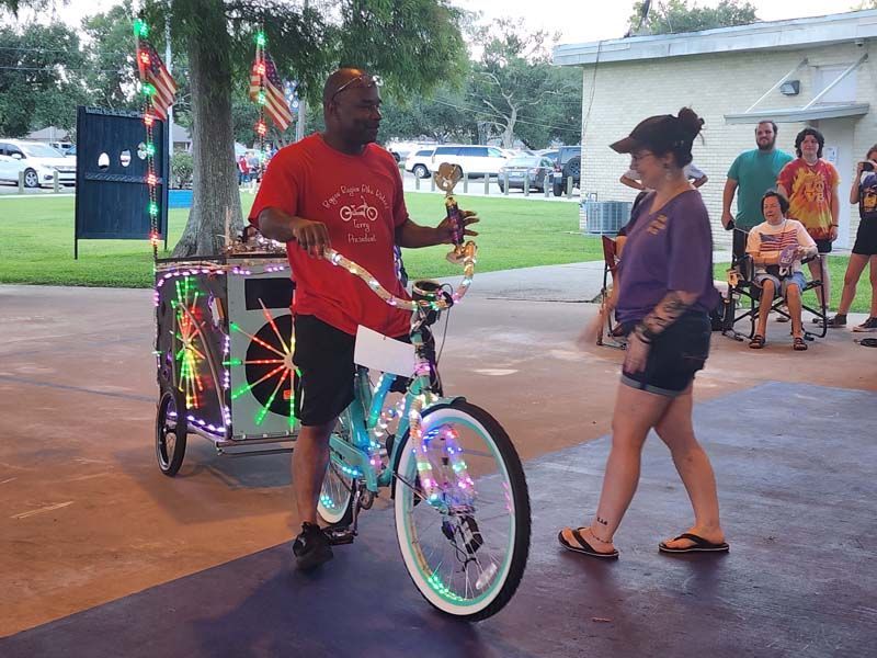A man is standing next to a bicycle with lights on it.