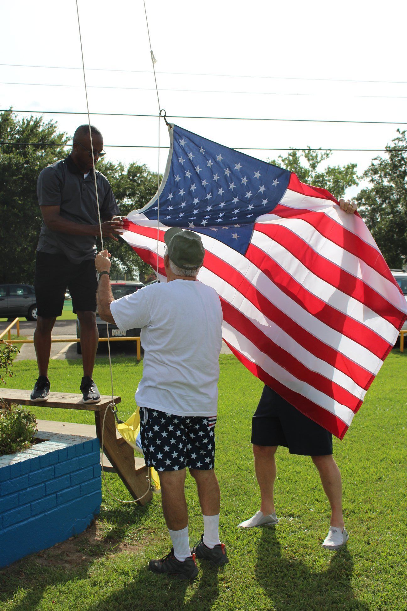 A man is holding a large american flag in a field