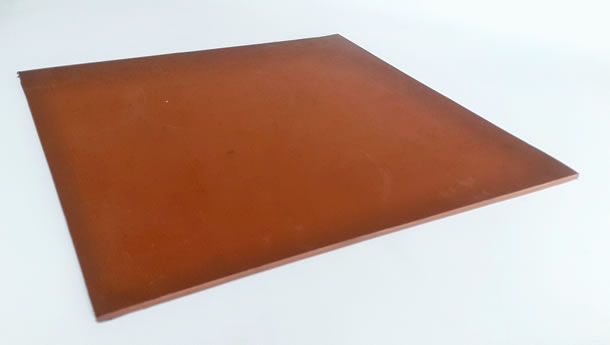 Un azulejo cuadrado marrón está sobre una superficie blanca.