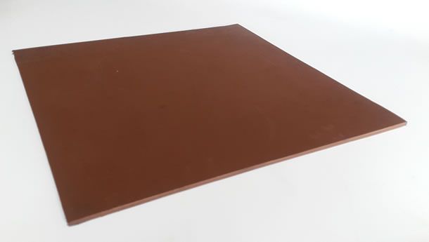 Un azulejo cuadrado marrón está colocado sobre una superficie blanca.