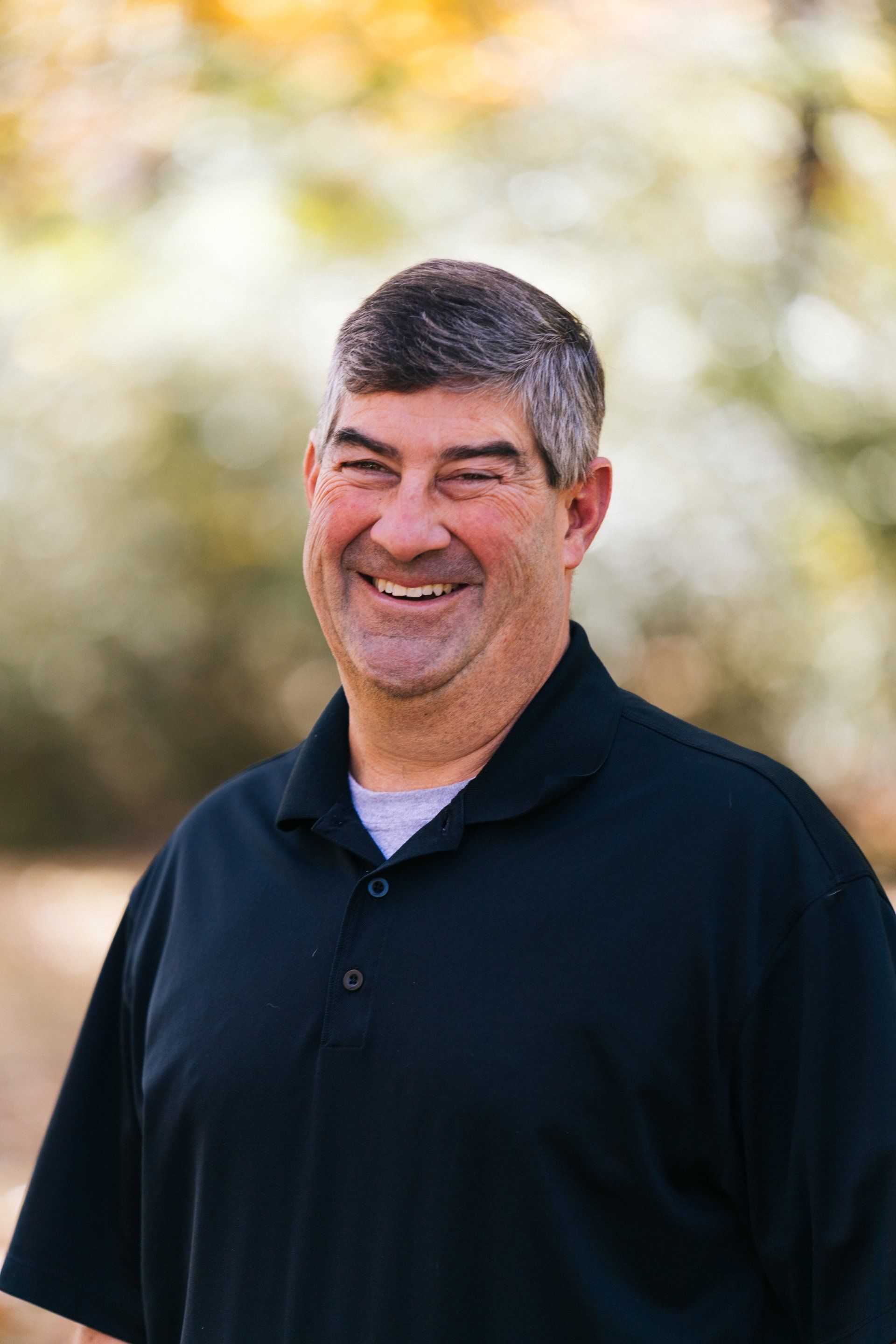 A man in a black shirt is smiling for the camera.