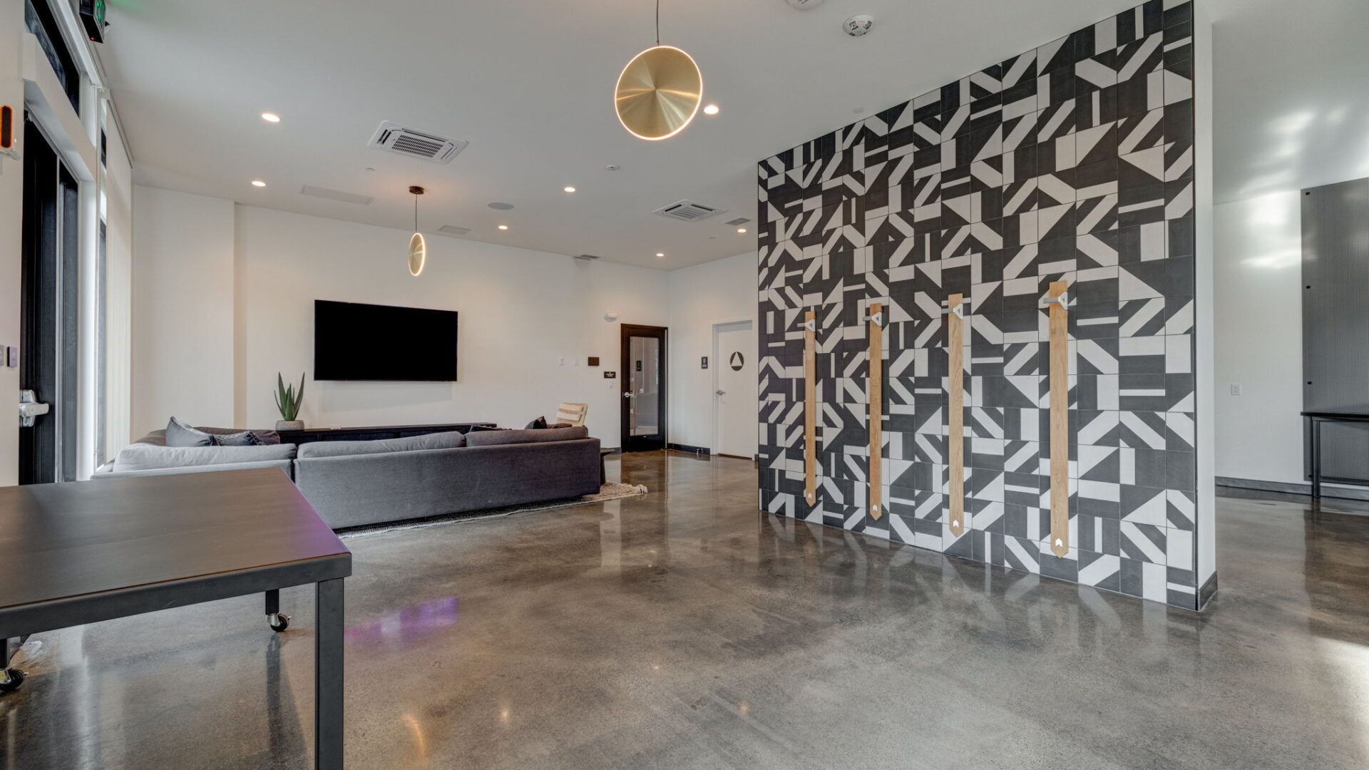 Modern lounge with gray sofa, patterned wall, and concrete floor at The Waymark in Walnut Creek, CA.