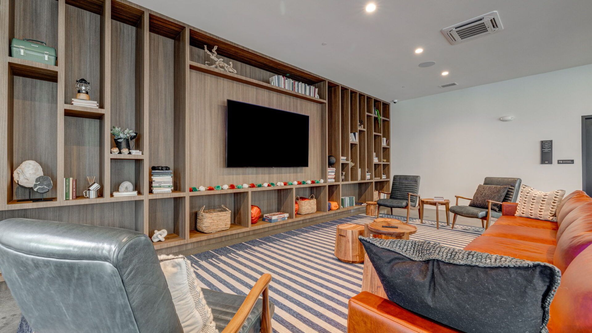 Modern living room with built-in shelving, TV, seating, and striped rug at The Waymark in Walnut Creek, CA.