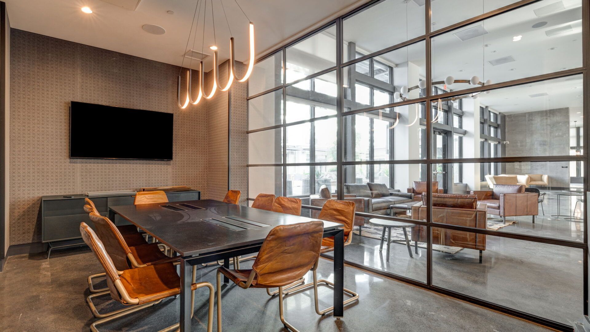 Conference room with long table, leather chairs, glass wall, TV, and neutral colors at The Waymark in Walnut Creek, CA.
