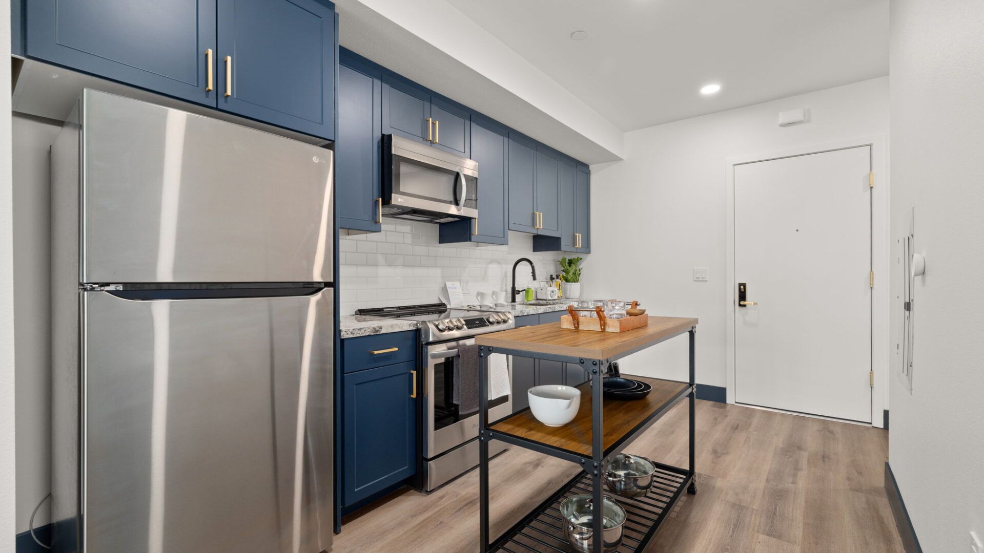 Modern kitchen with blue cabinets, stainless steel appliances, and an island at The Waymark in Walnut Creek, CA.