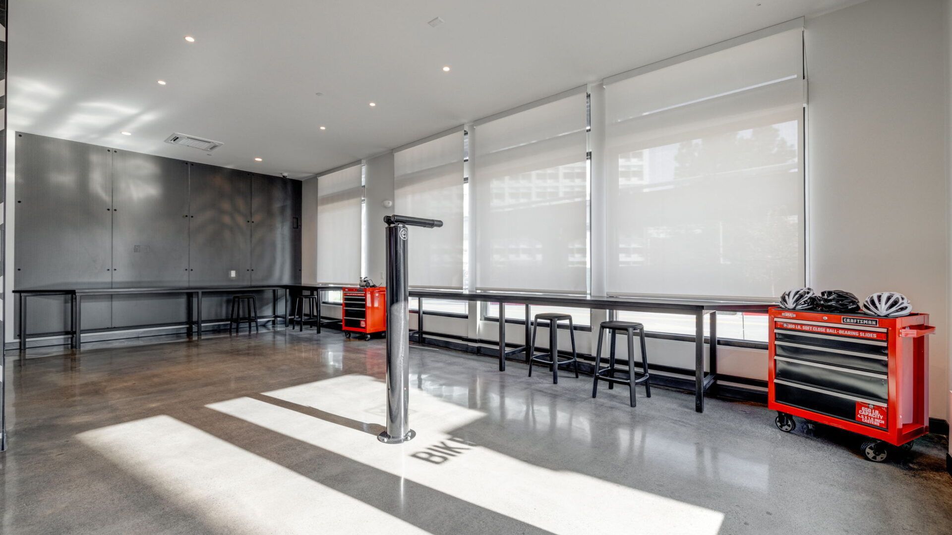 A modern workshop with workbenches, tools, and a bike repair stand. Bright light streams through the windows at The Waymark in Walnut Creek, CA.