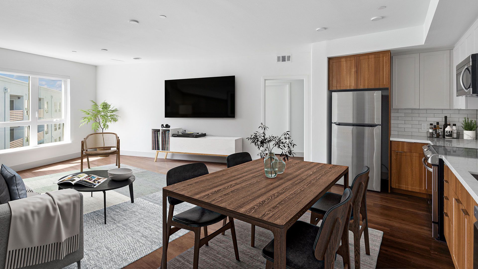 Living room with dining area and kitchen. Neutral tones with a tv, table and stainless steel appliances at The Waymark in Walnut Creek, CA.