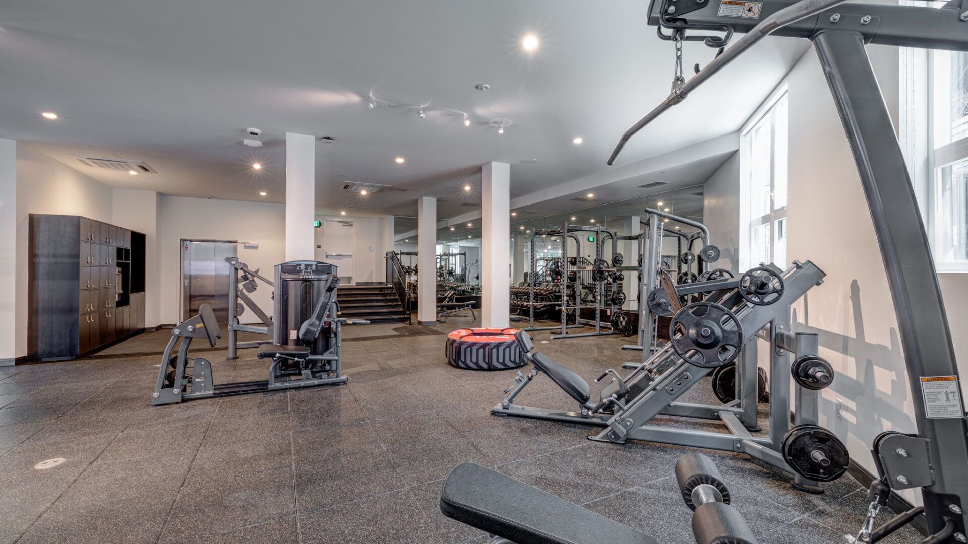 Gym interior with weight machines, a tire, and lockers at The Waymark in Walnut Creek, CA.