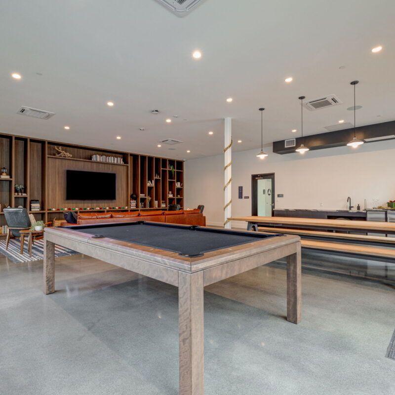 A modern game room with a pool table, seating, and a TV at The Waymark in Walnut Creek, CA.