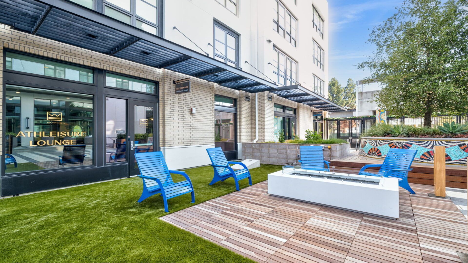 Outdoor patio with blue chairs, fire pit, and building at The Waymark in Walnut Creek, CA.