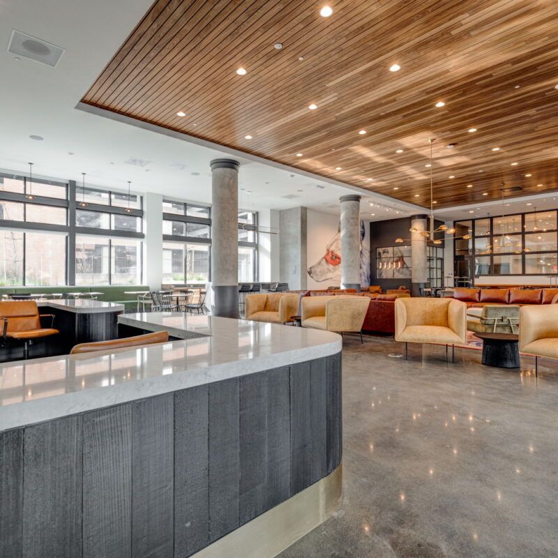 Modern lounge area with bar, seating, wooden ceiling, and concrete floor at The Waymark in Walnut Creek, CA.