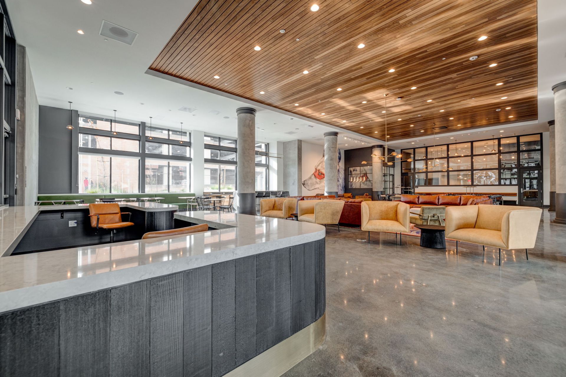 Lobby with bar, seating areas, and a wood-paneled ceiling. The space is modern, and the floors are polished concrete  at The Waymark in Walnut Creek, CA.
