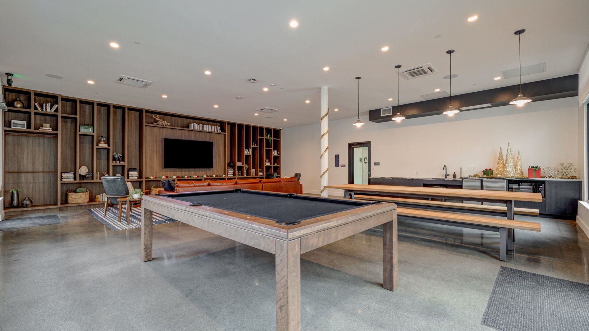 Spacious rec room with pool table, wooden shelving, and a long wooden table with benches at The Waymark in Walnut Creek, CA.